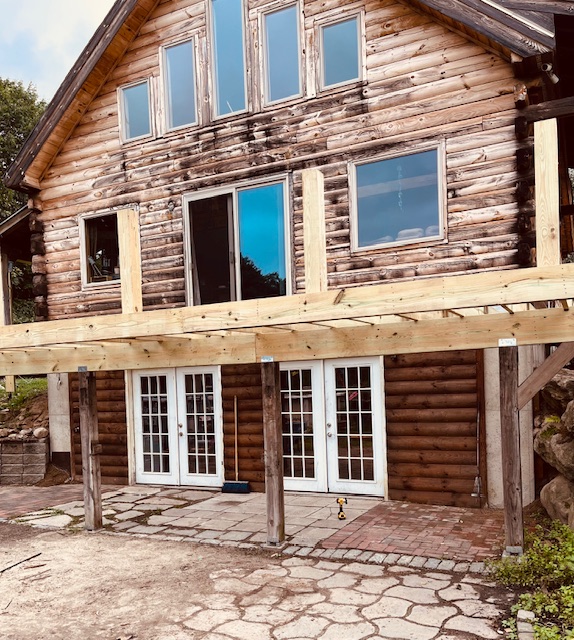 Wide exterior view of a large deck rebuild at a Goffstown log home